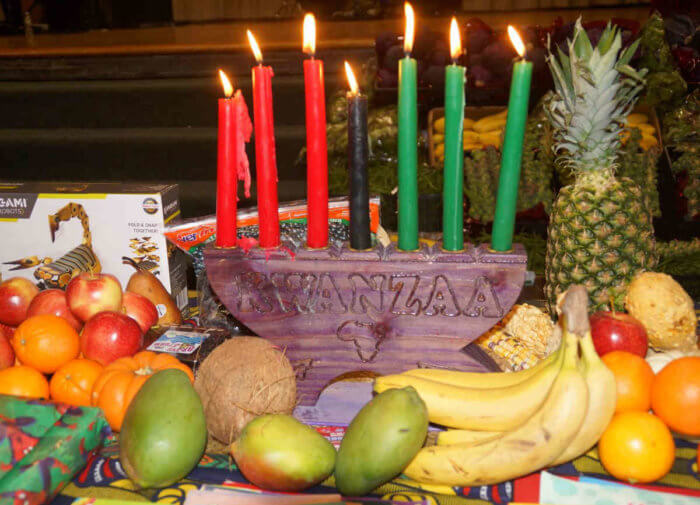 Kinara candles and symbols of Kwanzaa were featured at the annual holiday event.|Bombayo Dance Co. members gave a crowd pleasing performance.|Symbols of Kwanzaa adorned the stage.|Assemblyman Michael Blake celebrated Kwanzaa with Dustin.|(l-r) King Lagee, Debra Oguamah, Sarah Thomas and event emcee Nubia Grown welcomed everyone to the community celebration.|The Ancestral Drumming Band performed during the celebration.