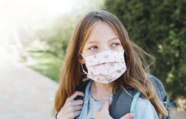 pretty girl with nose mouth mask goes to school