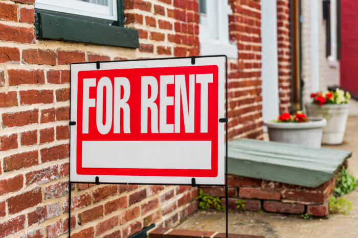 Red For Rent sign closeup against brick building