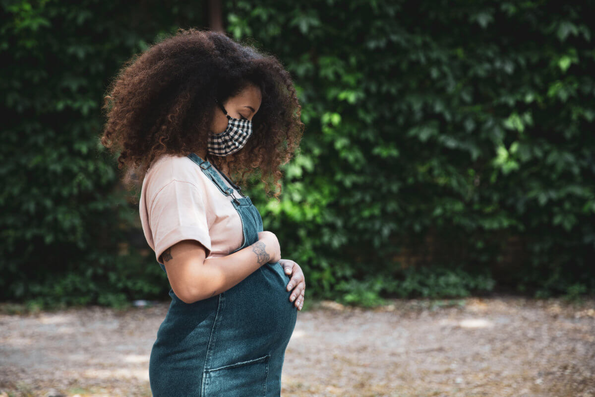 Pregnant afro hair woman in the city wearing a cloth protective mask