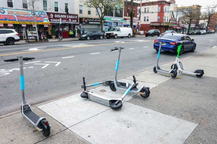 e-scooters parked on sidewalk, two are tipped over on the ground