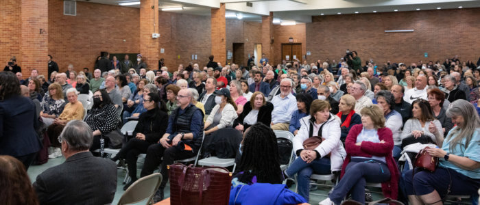 a crowd of people sit to discuss the Bruckner proposal