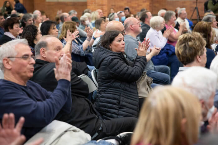 people clap their hands at a meeting to discuss the Bruckner proposal