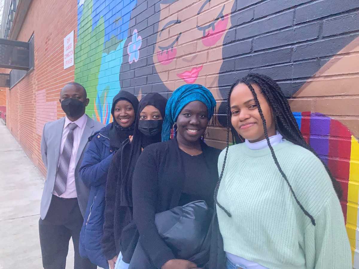 Susso and students in front of mural