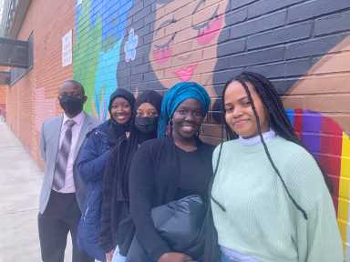 Susso and students in front of mural