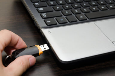 hand holding usb storage device with laptop