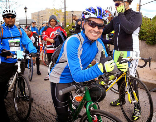 man smiles and holds two thumbs up on his bicycle 