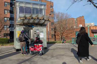 A commuter pulling a loaded cart waits for the elevator at the Utica Avenue station in Brooklyn, Dec. 15, 2020.