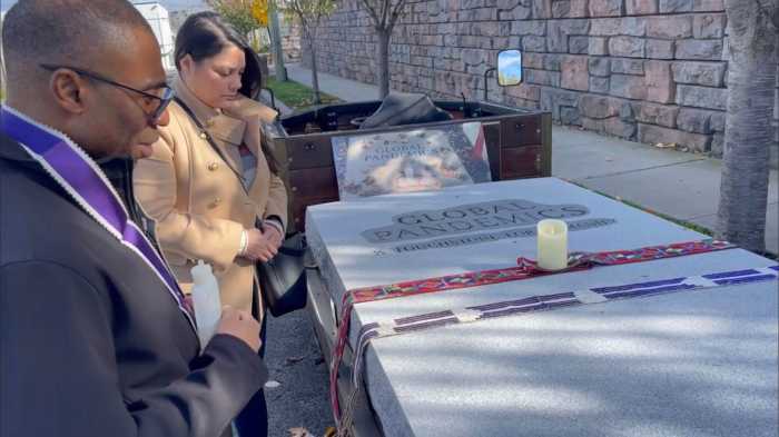 Advocates for the Hart Island touchstone project pray over the stone in October 2022.