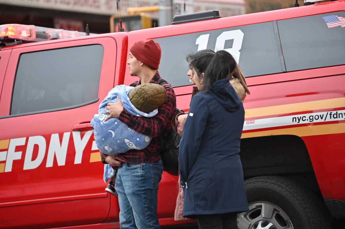 People watch on as firefighters work to bring the blaze under control in Soundview on Sunday, Jan. 29, 2023.