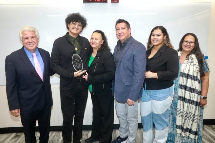 Moujan Vahdat, left, presents Lehman College student Matthew Garaicoa, second from left, with the first annual Race Unity Awards. Garaicoa attended the awards ceremony with his family, to his right.
