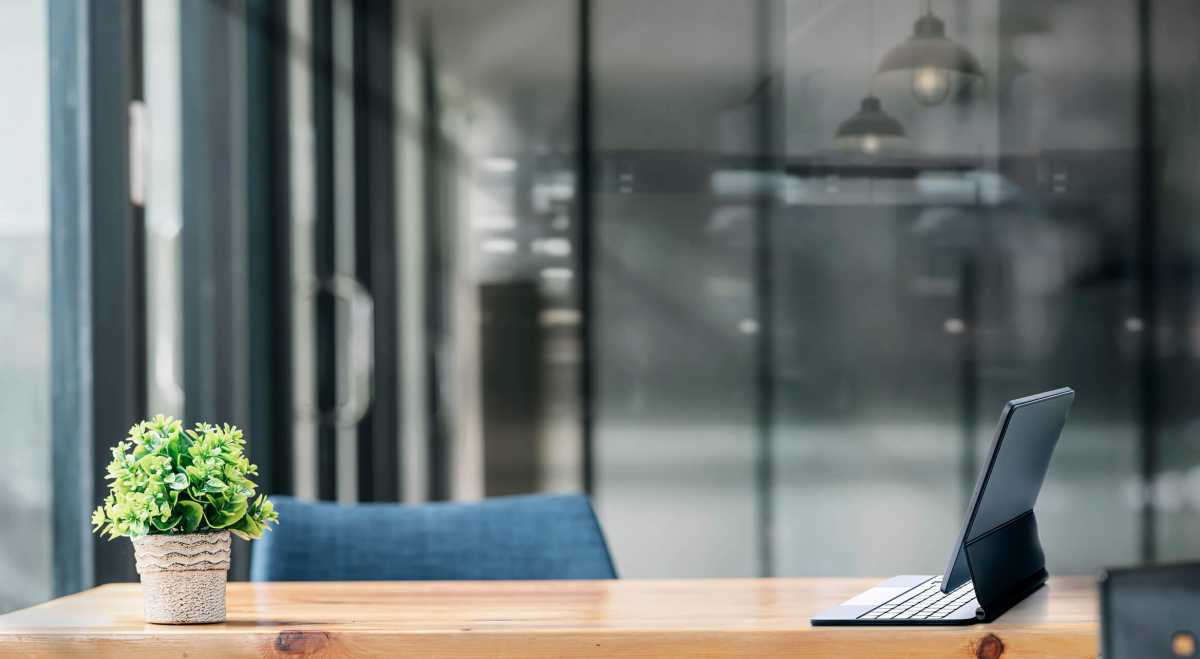 Mockup tablet with magic keyboard on wooden tablet in dark tone office room.
