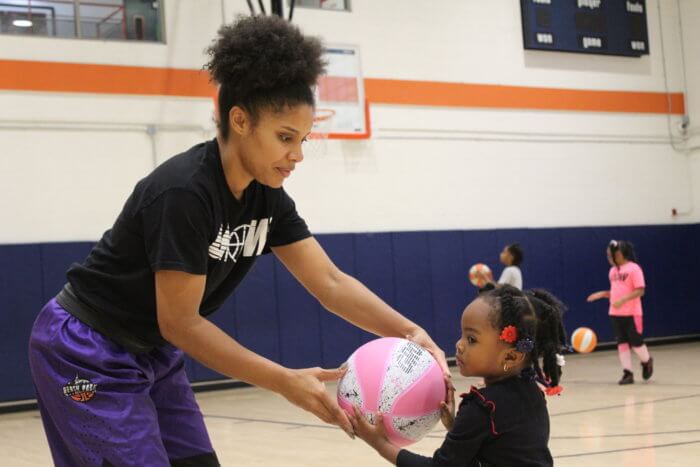 Chiené Joy Jones helps 3-year-old Ari-Joi Gladden with her form during a Grow Our Game basketball practice in East New York, Brooklyn on Saturday, Dec. 10, 2022.