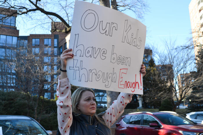 A parent holds up a sign that reads “our kids have been through enough” during the rally against St. Gabriel’s School’s potential closure in Riverdale on Tuesday, Feb. 14, 2023. Some parents said it has been difficult trying to recover from the COVID-19 pandemic.
