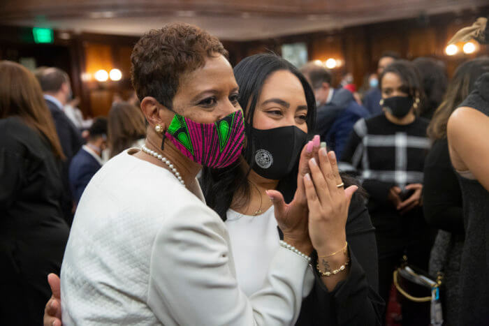 Speaker Adams and Councilmember Farías hold their hands up while embracing one another