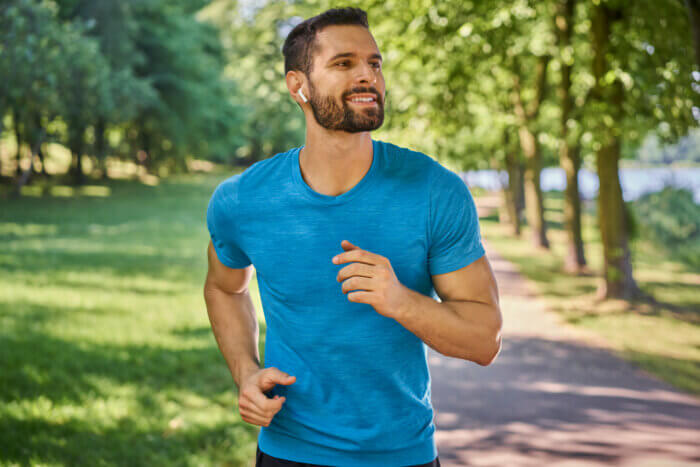 Man running in the park with earphones on a nice and sunny day.