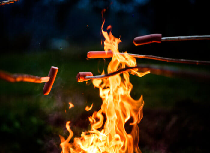 Cooking hotdogs over an open camp fire