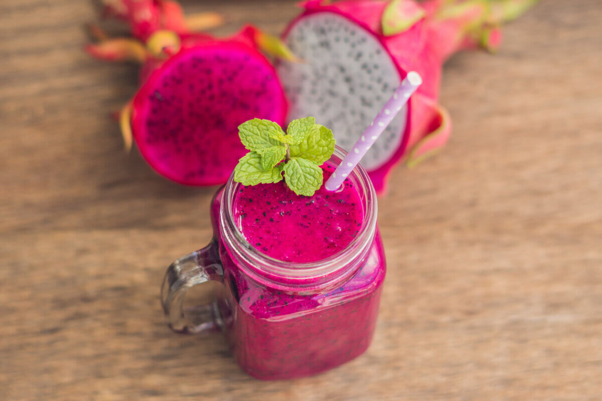 Red dragon fruit smoothie on a wooden background.
