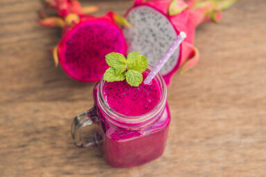 Red dragon fruit smoothie on a wooden background.