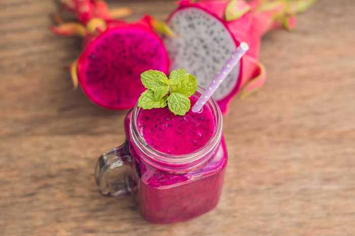 Red dragon fruit smoothie on a wooden background.