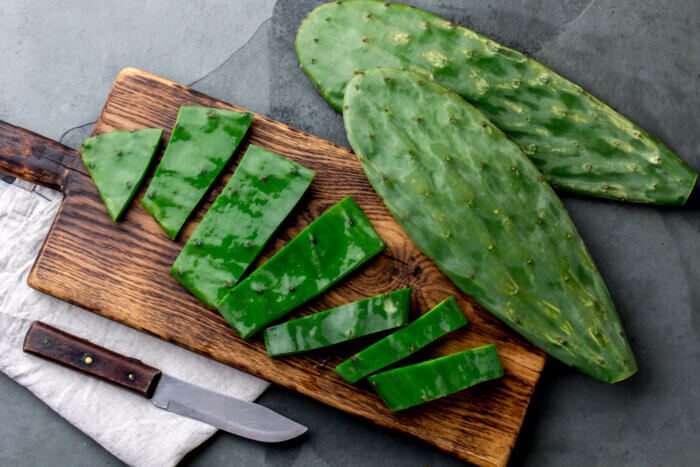 Chopped leaves of a prickly pear cactus on a cutting board.