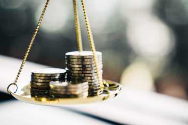 Coins stacked on one side of a scale, blurred background.