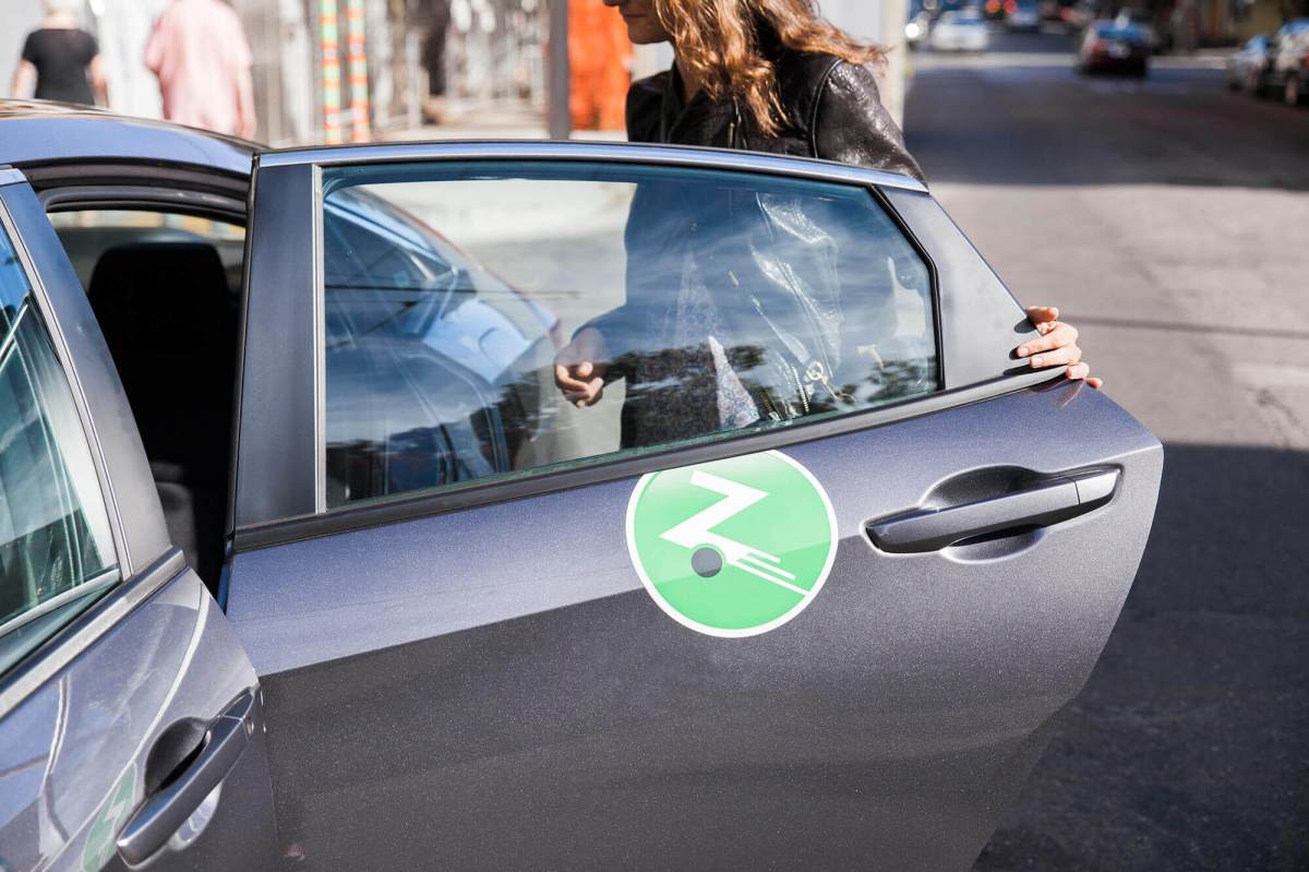 Lady opening grey Zipcar car door.