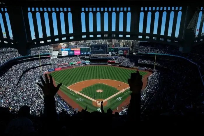 A fan's hands are in the air, cheering at the Yankees game.