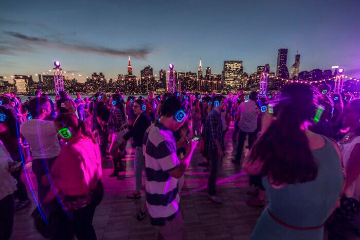 Silent disco party in the evening with the NYC skyline in the background.