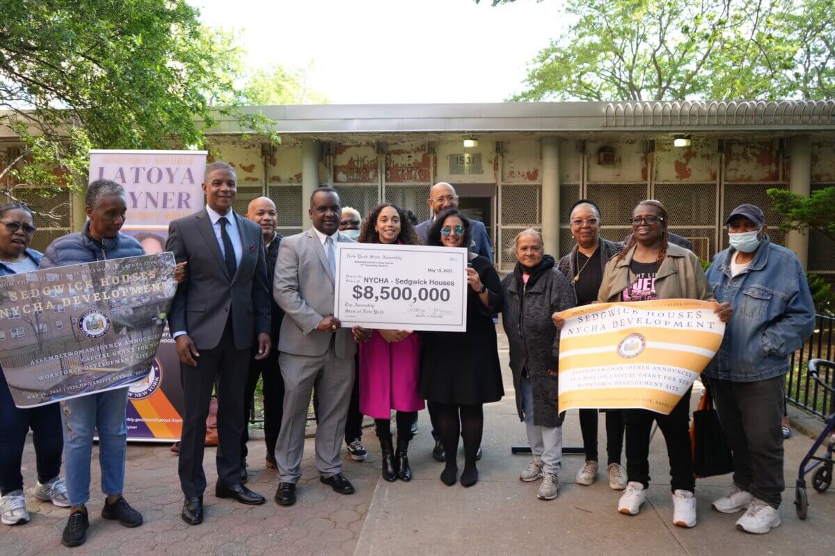 people pose with a symbolic $8.5 million check