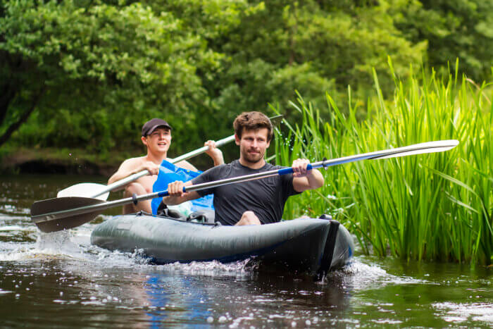 Kayaking on the river. Two friends in a boat sailing along the river. Rowers with oars in a canoe. Rafting on a kayak. Leisure. Young men are rafting along a wild river. Bronx