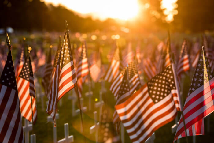 Small american flags on a field of grass in front of a sunset. Happening
