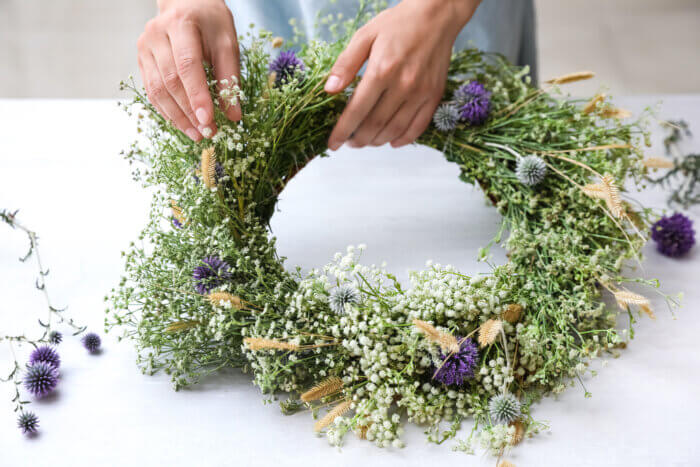 Hands holding a wreath made with small wildflowers. Bronx