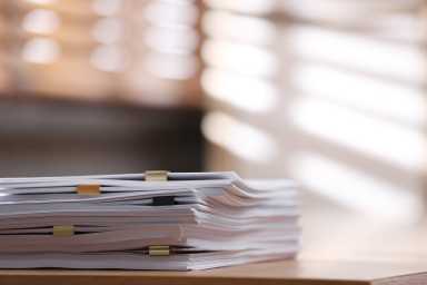 Stack of blank paper with binder clips on wooden table indoors. Space for text