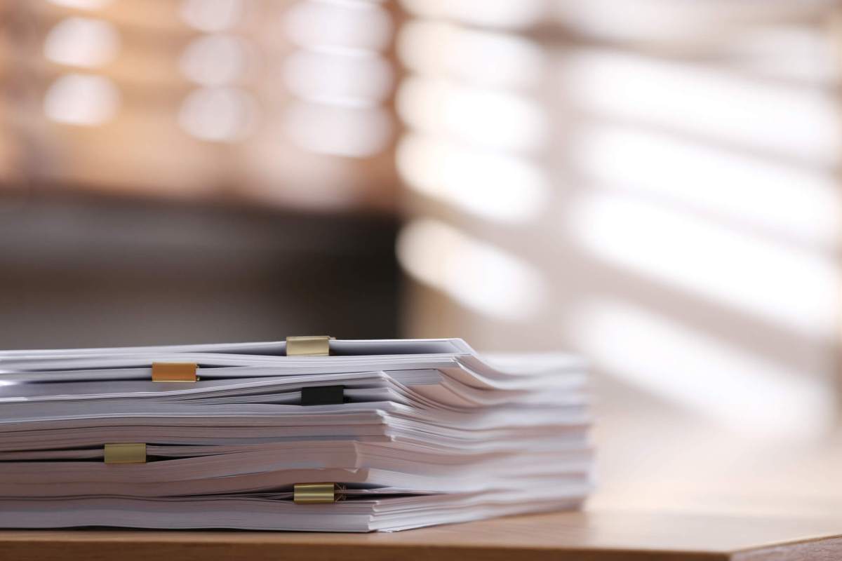 Stack of blank paper with binder clips on wooden table indoors. Space for text