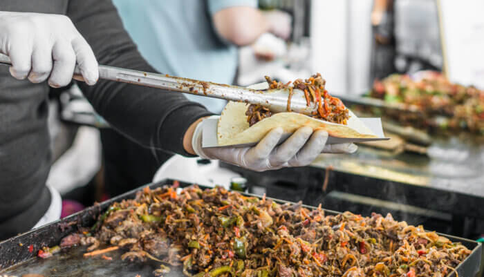 Closeup of a chef at a street food market preparing a taco. Bronx