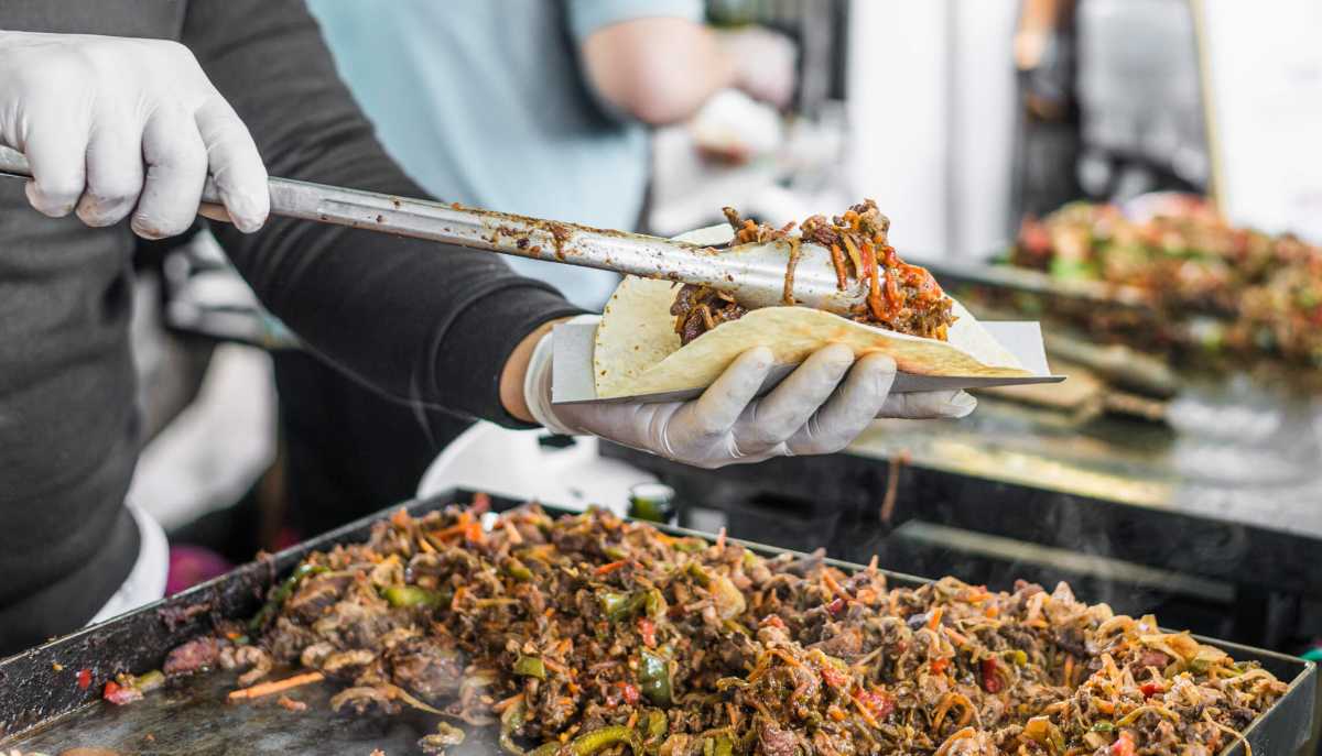 Closeup of a chef at a street food market preparing a taco. Bronx Night Market.
