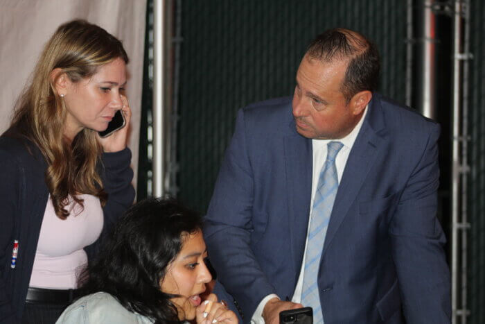 Kristy Marmorato holds a phone while looking at a phone her campaign manager is looking at. Michael Rendino looks at Kristy Marmorato.