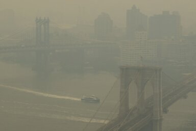 In a view toward Brooklyn, a boat maneuvers the East River near the Manhattan Bridge, left, and Brooklyn Bridge in New York on Wednesday, June 7, 2023. Smoke from Canadian wildfires is pouring into the U.S. East Coast and Midwest and covering the capitals of both nations in an unhealthy haze.