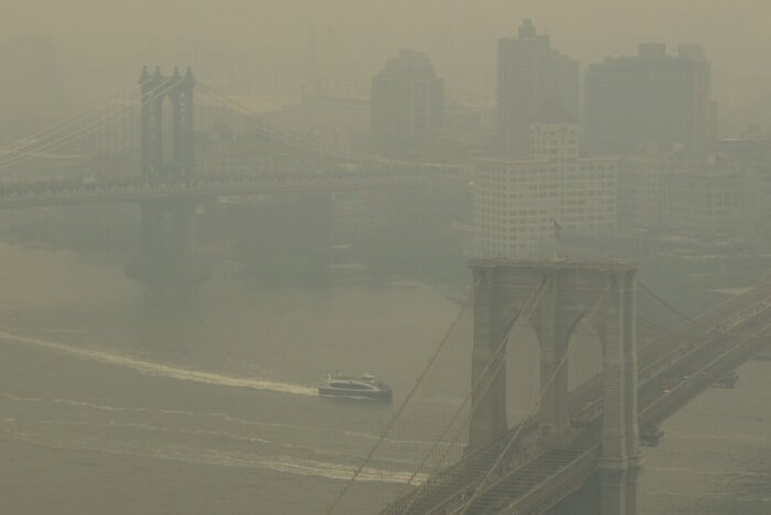 In a view toward Brooklyn, a boat maneuvers the East River near the Manhattan Bridge, left, and Brooklyn Bridge in New York on Wednesday, June 7, 2023. Smoke from Canadian wildfires is pouring into the U.S. East Coast and Midwest and covering the capitals of both nations in an unhealthy haze.