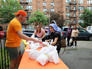 Brett Swanson, senior manager of community affairs and social impact at Grub Hub, helps distribute 500 free meals to passersby at the Pelham Parkway Houses on June 26, 2023.