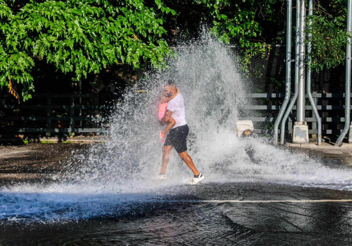 People walk through a spray shower in an attempt to beat the heat.