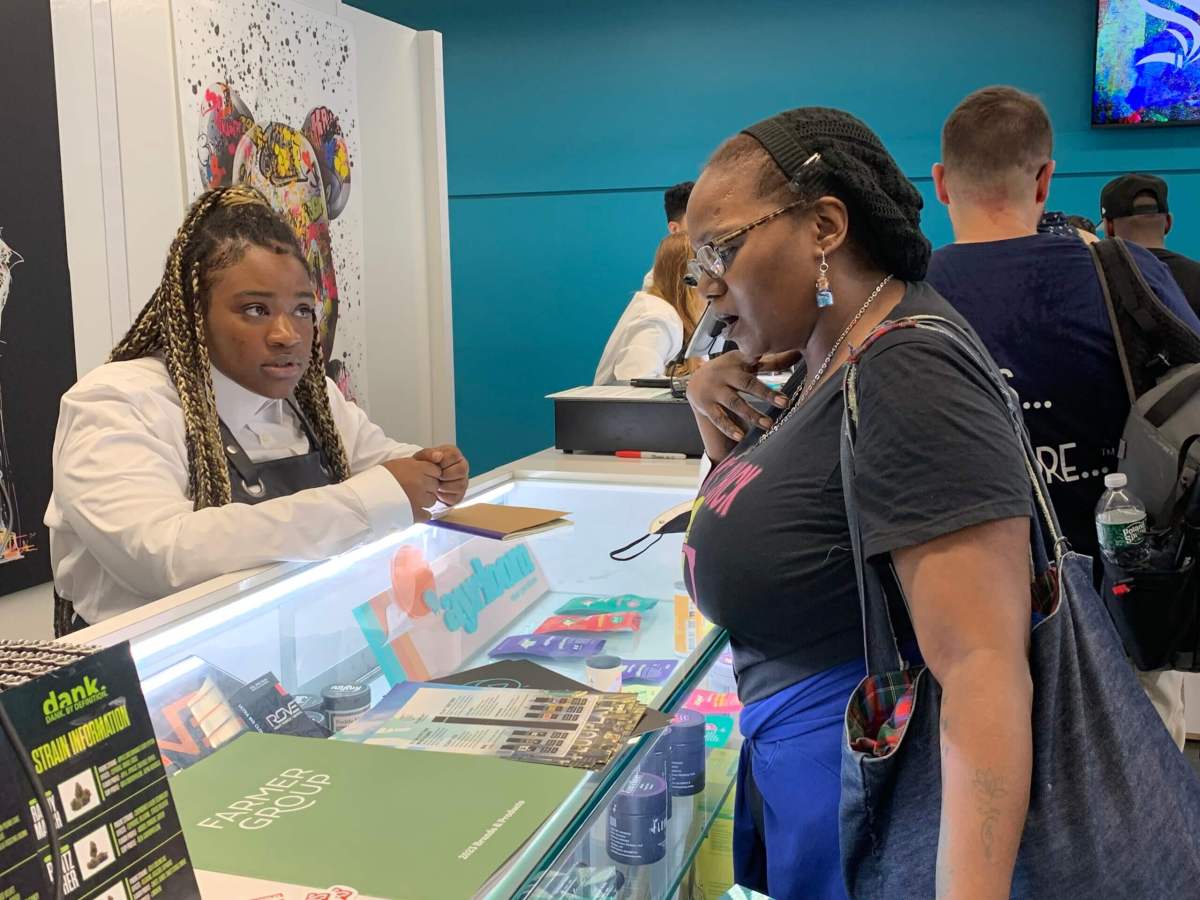 customer looks at merchandise at cannabis dispenary counter as dispensary employee looks at the customer