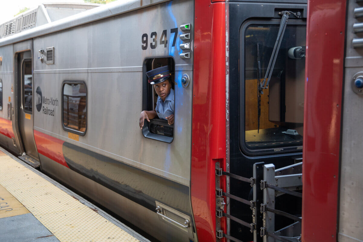 a conductor looks out the window of a Metro North train car