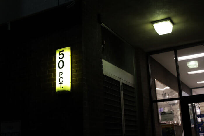 sign lit up at night says 50th precinct