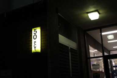 sign lit up at night says 50th precinct