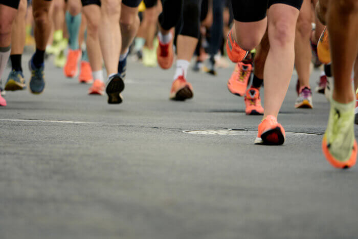 Marathon running race, people feet on city road.