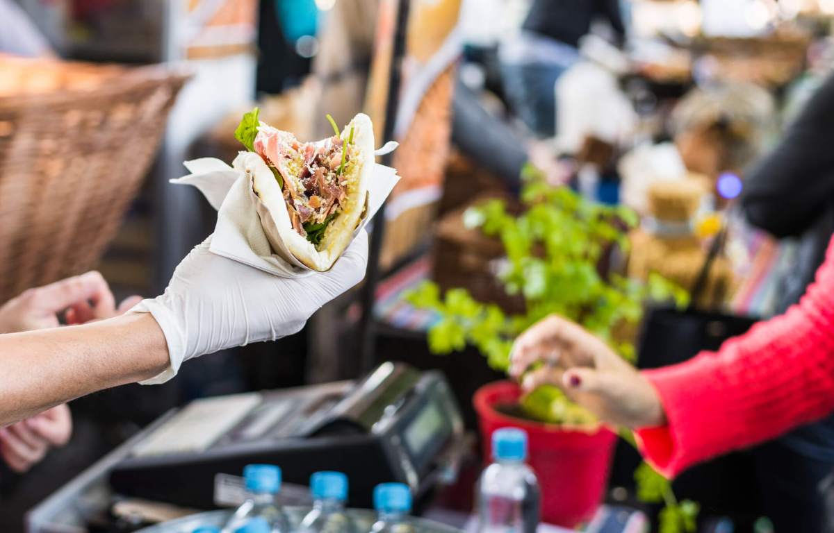 Chef handing a tortilla to a foodie at a street food market