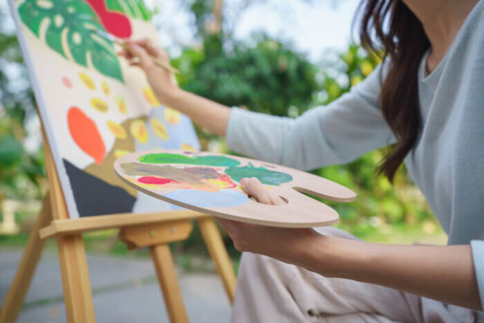 Outdoor activity concept, Female artist painting on canvas with paintbrush and watercolor in garden