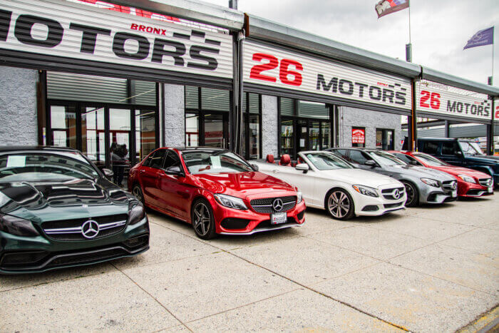 Luxury cars are parked outside of 26 Motors.